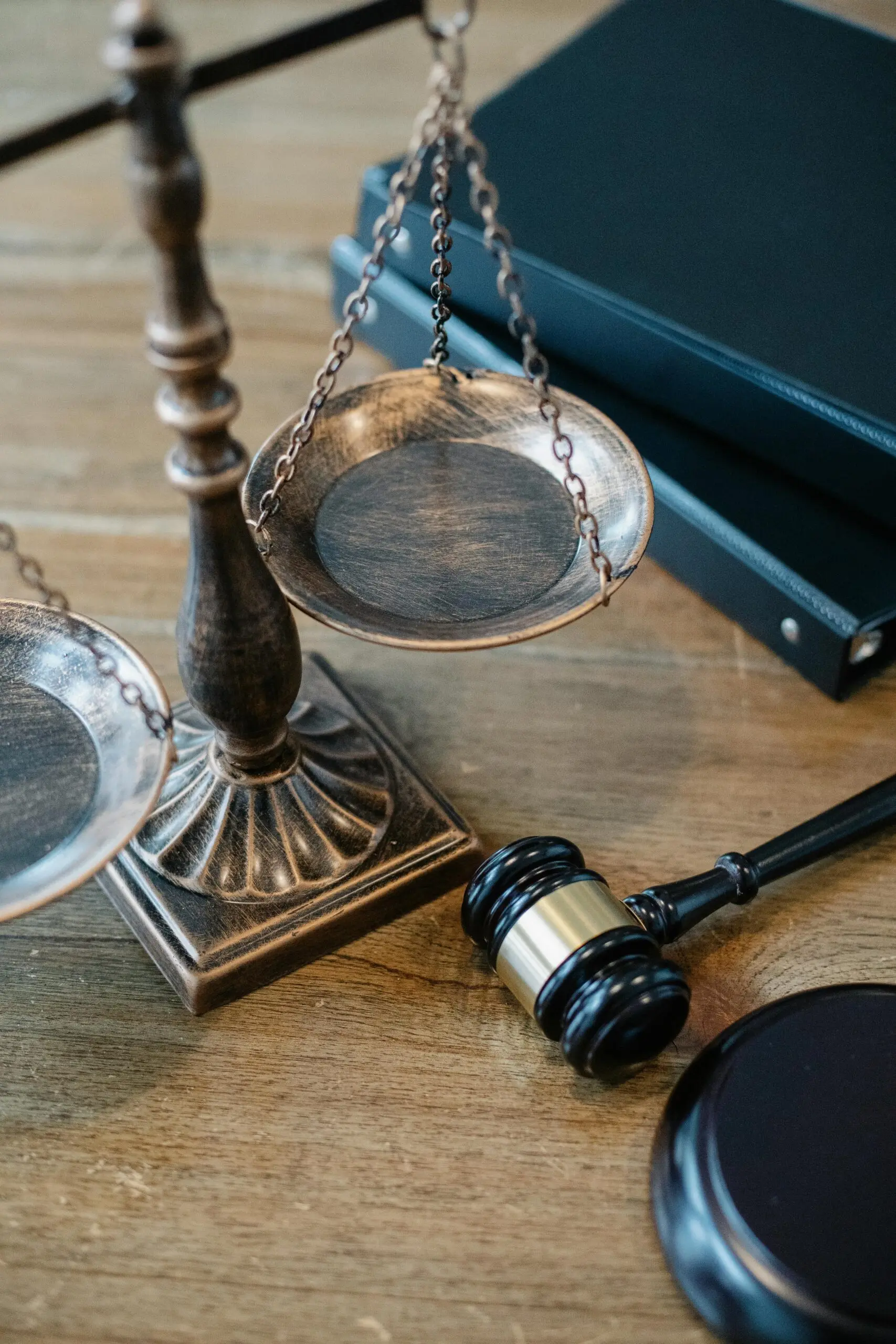 Balanza de la justicia y mazo junto a libros de derecho sobre una mesa de madera de angazalegal
